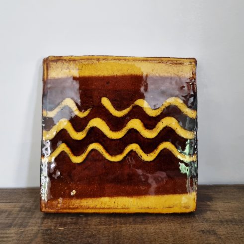 glazed earthenware tile with slip decoration featuring waves by Clive Bowen