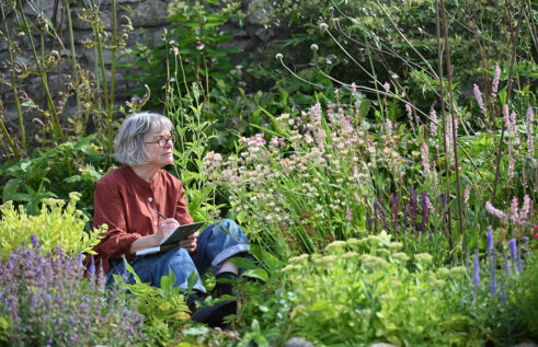 Angie Lewin drawing in her garden, 2026